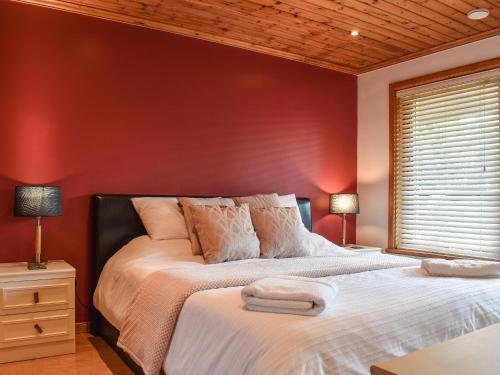 a bedroom with a large bed with a red wall at Madison in Jacobstow