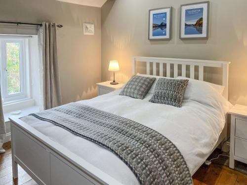 a bedroom with a large white bed with two pillows at Smithy Cottage in Keldhead
