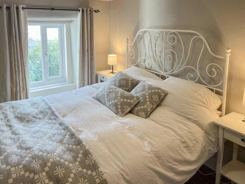 a white bed with two pillows on it with a window at Smithy Cottage in Keldhead