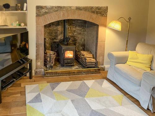 ein Wohnzimmer mit Kamin und Ofen in der Unterkunft Smithy Cottage in Keldhead