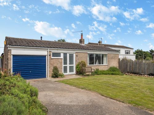 a brick house with a blue garage at Little Dab in Brancaster