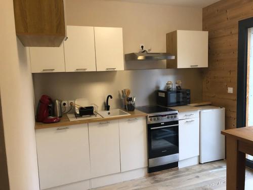 une cuisine avec des armoires blanches et un four à plaques de cuisson dans l'établissement Independent studio in a chalet, à Mont-Saxonnex