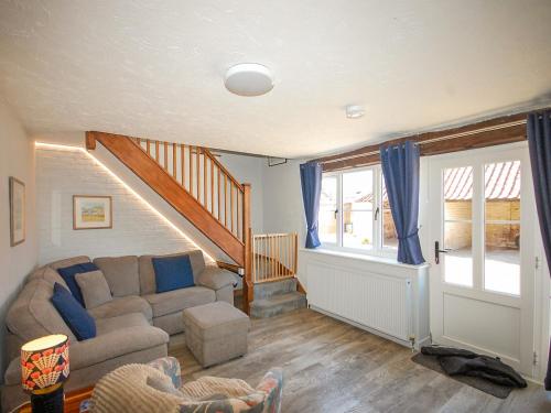 a living room with a couch and a staircase at Wherry Cottage in Wells next the Sea