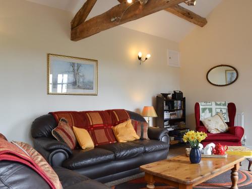 ein Wohnzimmer mit einer Ledercouch und einem Tisch in der Unterkunft Brampton Hill Farm Cottage in Madley
