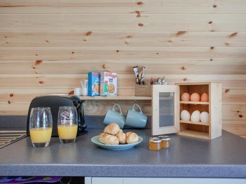 a kitchen counter with two glasses of orange juice and bread at Glamping Pod 2 in Ipplepen