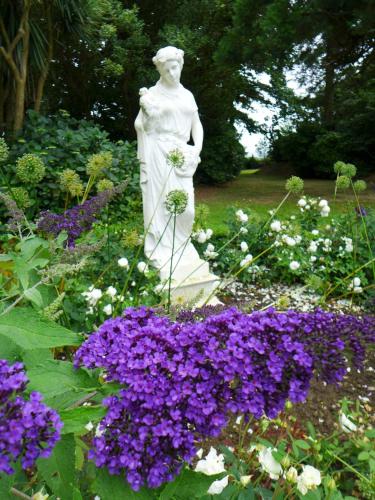 a statue of a woman in a garden with purple flowers at Tinakilly Country House Hotel in Rathnew