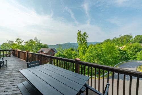 a wooden deck with a bench and a view of the mountains at Whiskey Hills - Newly Remodeled Luxury Cabin with Hot Tub, Incredible Views close to Asheville, walk to Hatley Pointe & Ski! in Swiss