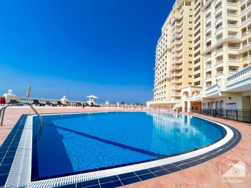 a swimming pool in front of a large building at 1BR Getaway in RAK l Balcony , Pool and Gym Access in Ras al Khaimah