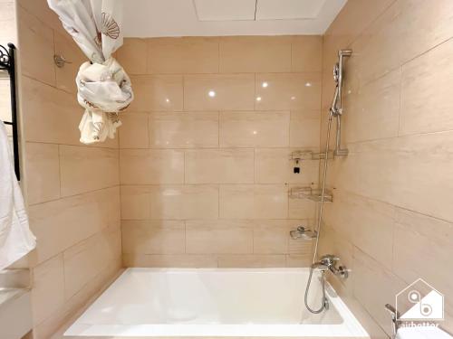 a bathroom with a bath tub and a shower at 1BR Getaway in RAK l Balcony , Pool and Gym Access in Ras al Khaimah
