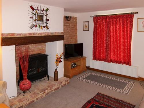 a living room with a fireplace and a television at Hollyhocks Cottage in Docking