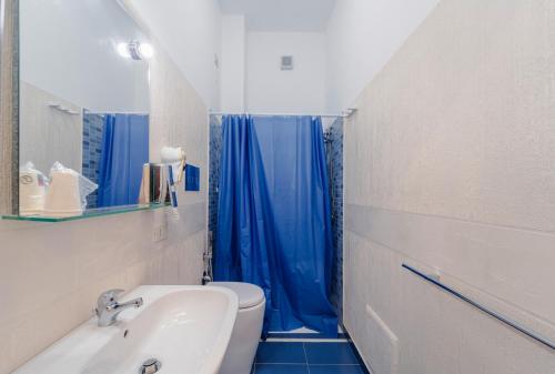 a bathroom with a toilet and a blue shower curtain at "L'Oasi di Favignana" Room and Charme in Favignana