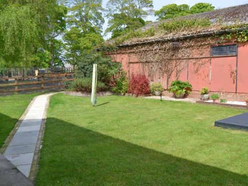 a garden with a building and a grass yard at The Old Stables in Freethorpe