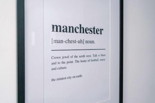 a white framed picture of a manchester sign at The Definition Apartment in the Northern Quarter by Rest&Recharge in Manchester