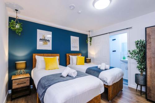 two beds in a room with blue walls at The Definition Apartment in the Northern Quarter by Rest&Recharge in Manchester