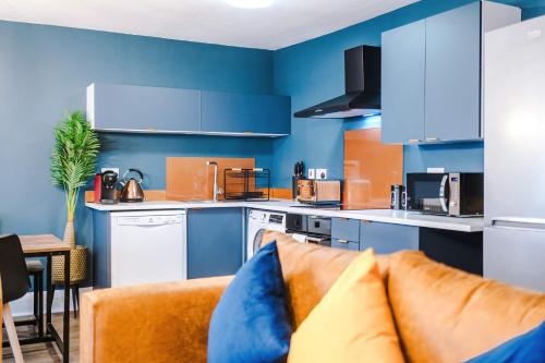 a kitchen with blue cabinets and a couch in a room at The Definition Apartment in the Northern Quarter by Rest&Recharge in Manchester