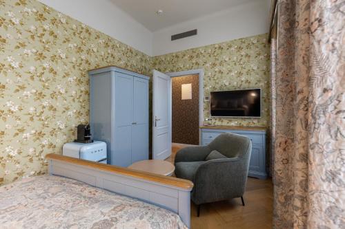 a bedroom with a bed and a chair and a television at Roze Boutique Apartments in Liepāja