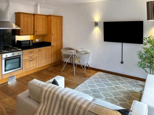 een woonkamer met een bank en een tv aan de muur bij Oak in Falmouth