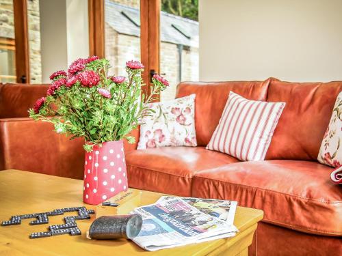 a brown leather couch with a vase of flowers on a table at The Farmhouse At Gradbach in Flash