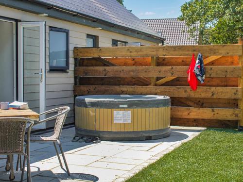 a wooden fence with a hot tub next to a table and chairs at No 1 Fox Burrow-Uk44306 in Lenwade