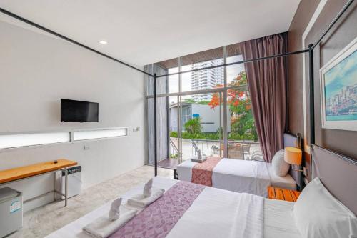a hotel room with two beds and a window at Sunset Serenity Jomtien Resort in Na Jomtien