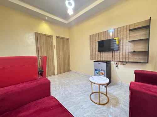 a living room with a red couch and a tv at Amnu Homes Apartment in Ilorin