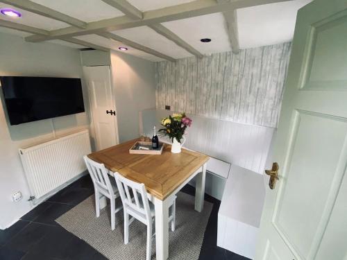 a dining room table with white chairs and a television at The Old Toll House in Coalport