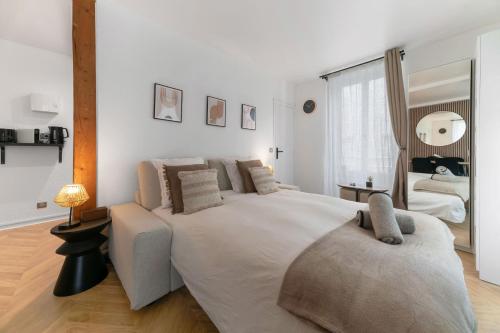 a white bedroom with a large bed and a mirror at Résidence Serbie - Appartements design et climatisés en centre ville in Vichy