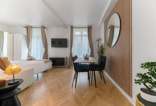 a room with a bed and a table and a mirror at Résidence Serbie - Appartements design et climatisés en centre ville in Vichy