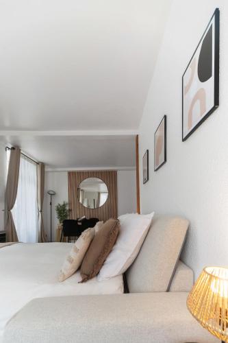 a bedroom with a white bed with pillows on it at Résidence Serbie - Appartements design et climatisés en centre ville in Vichy