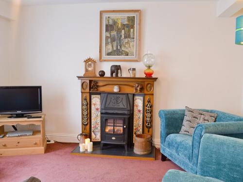 sala de estar con chimenea y sofá azul en Bert's Cottage, en Fordingbridge