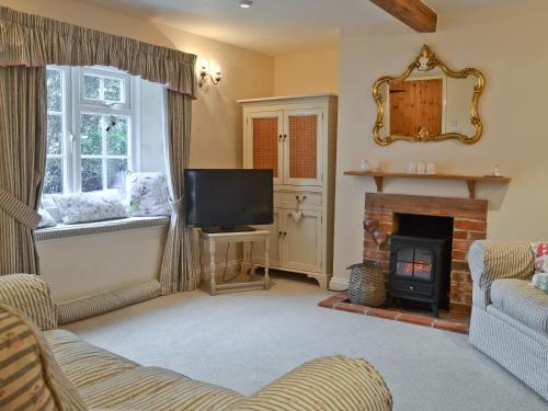 a living room with a fireplace and a television at Sweet Pea Cottage in Heacham