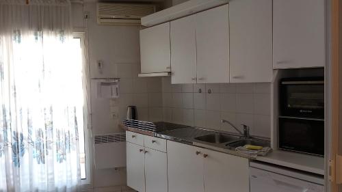 une cuisine avec des armoires blanches, un évier et une fenêtre dans l'établissement Calm Flat, à Cannes