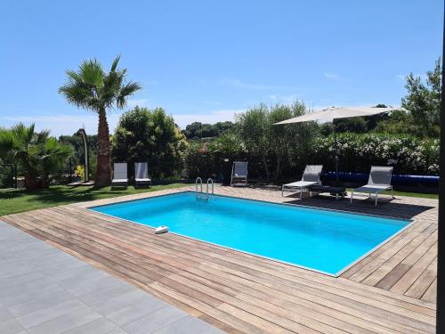 une piscine avec une terrasse en bois et deux chaises et un parasol dans l'établissement VILLA Loakel, à La Gaude