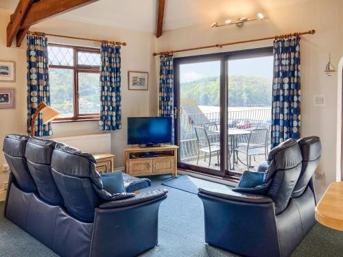 ein Wohnzimmer mit Stühlen und Fernseher und ein Balkon in der Unterkunft Marine Mews 3 - Cottage in Salcombe