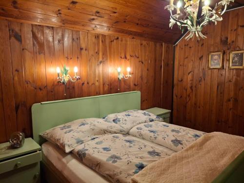 a bedroom with a bed with wooden walls and a chandelier at Waldpoesie - Das Wald-Cottage in Benking