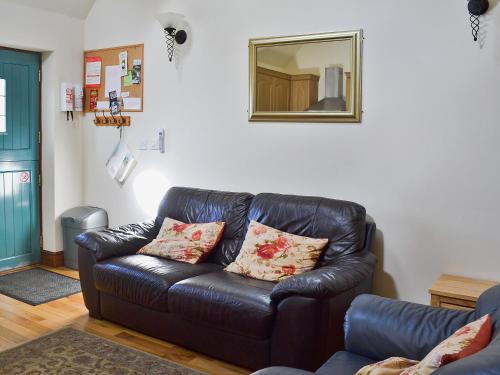a black leather couch in a living room with a mirror at Rose Cottage - 30502 in West Firle