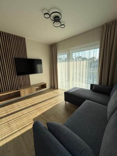 a living room with a couch and a flat screen tv at Czarna Perła Hel in Hel