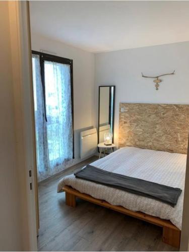 une chambre avec un grand lit et une fenêtre dans l'établissement Bel appartement avec piscine et proche plage, à La Rochelle