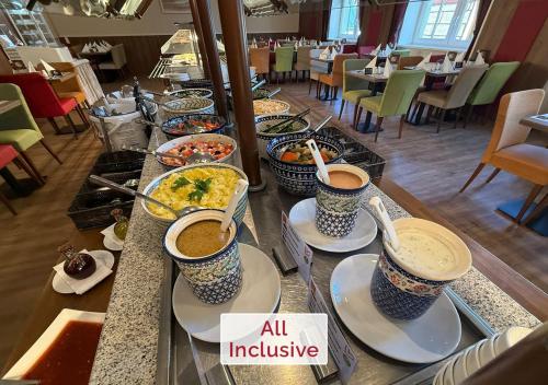 a buffet line with bowls of food and cups of coffee at Rathaushotels All Inklusive in Kurort Oberwiesenthal