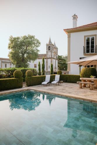 a swimming pool with two chairs and a building at Quinta do Bonfim in Portalegre