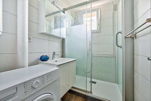 La salle de bains est pourvue d'un lave-linge et d'une douche en verre. dans l'établissement Michelet, à Ivry-sur-Seine