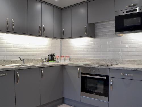 a kitchen with gray cabinets and stainless steel appliances at The Milking Parlour - Uk30866 in St Bees