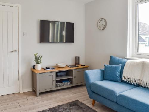 Una sala de estar con un sofá azul y un televisor. en Hillside At Bowness, en Windermere