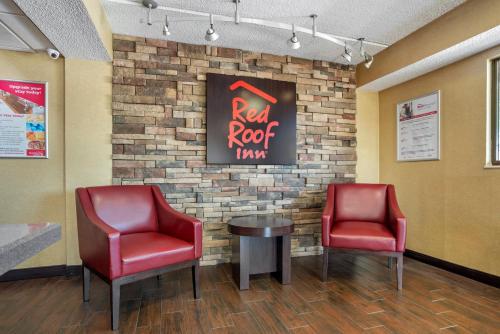 a waiting room with two red chairs and a table at Red Roof Inn West Monroe in West Monroe