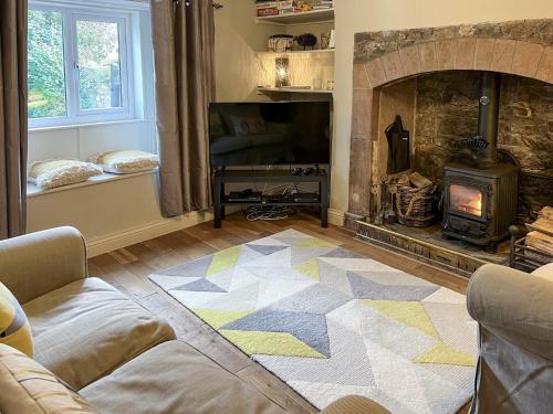 ein Wohnzimmer mit Kamin und Couch in der Unterkunft Smithy Cottage in Keldhead