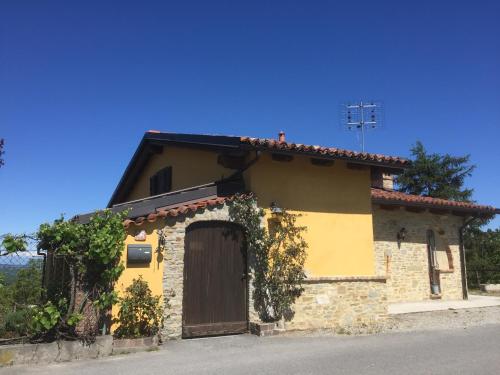 a yellow house with a brown door and vines at Ciabòt Taricchi in Dogliani