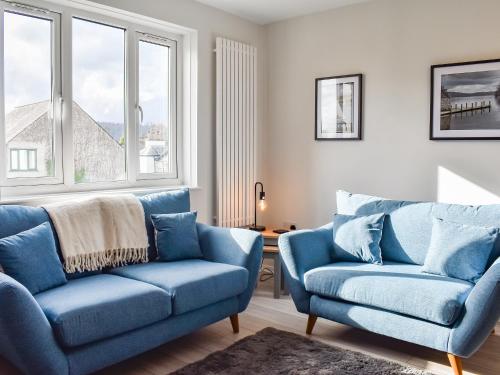 sala de estar con 2 sillas azules y ventanas en Hillside At Bowness, en Windermere