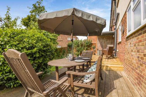 a wooden table and chairs with an umbrella on a patio at Cornerways by Bloom Stays in Canterbury