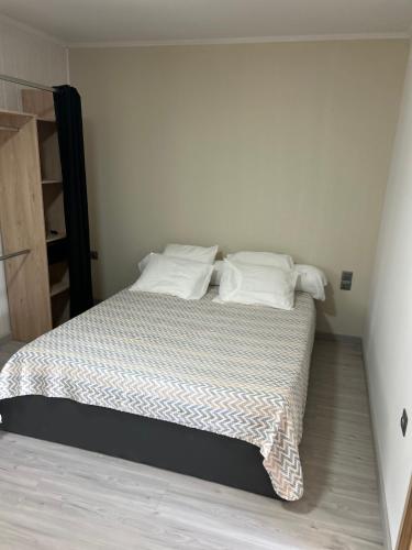 une chambre avec un lit avec des draps blancs et des oreillers dans l'établissement Appartement plain-pied 4 couchages, à Biguglia