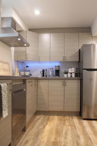 a kitchen with wooden cabinets and a stainless steel refrigerator at Queen Bed Suite-Private Entrance in Barrie